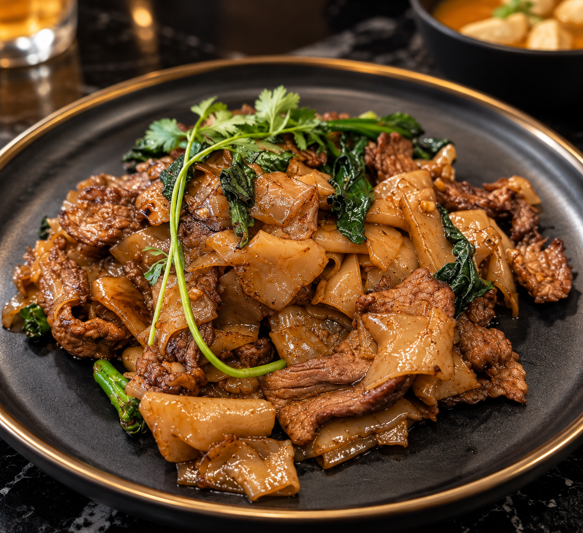 Beef Pad See Ew with wide rice noodles on a black plate